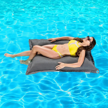 Woman lying on a gray beanbag pool float in a pool