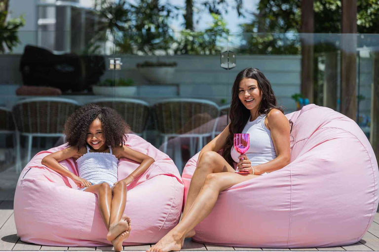 girls sitting on pink beanbag chairs by the pool