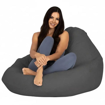 Woman sitting on a large gray bean bag chair against a white background