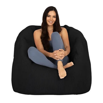 Woman sitting on a large black bean bag chair against a white background