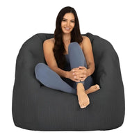 Woman sitting on a large dark gray bean bag chair against a white background