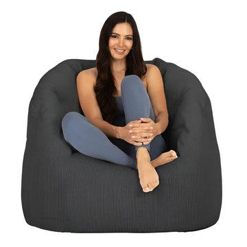 Woman sitting on a large dark gray bean bag chair against a white background