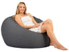 Woman sitting on a gray bean bag chair against a white background