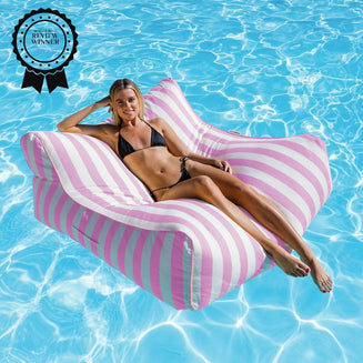 Woman lounging on a pink striped bean bag pool float in clear blue water with a 'Product Review Winner' badge.