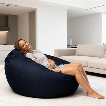 Woman sitting on a navy denim bean bag in a modern living room.