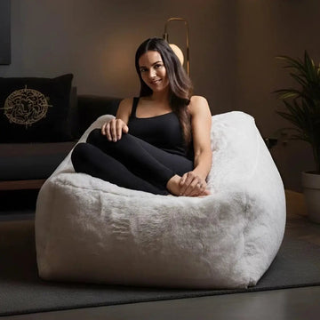 Woman sitting on a white bean bag chair in a dimly lit room.