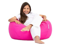 Young girl sitting on a pink bean bag chair against a white background