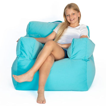 Young girl sitting on a large capri-blue bean bag chair against a white background