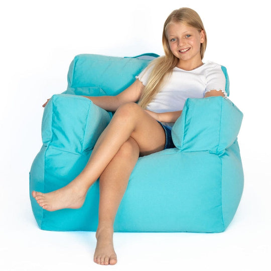Young girl sitting on a large capri-blue bean bag chair against a white background