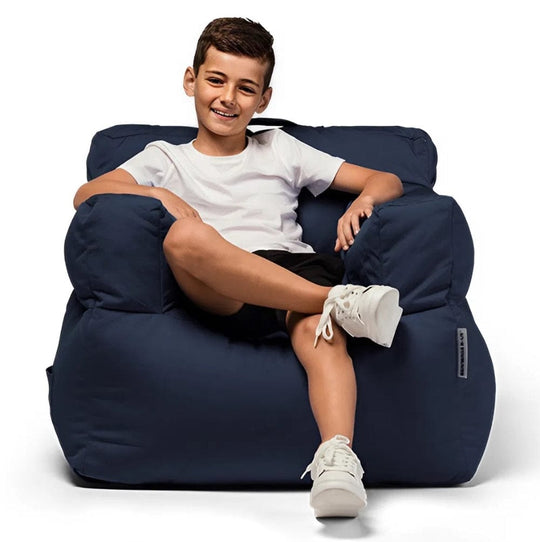 Child sitting on a navy bean bag chair against a white background